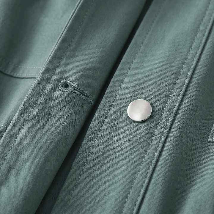 Close-up of green overcoat snap button and stitched flap detailing