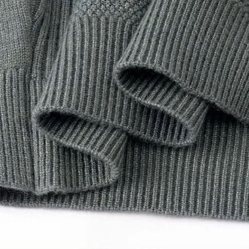 Gray-green jacquard sweater knit close-up with ribbed cuff and hem detail