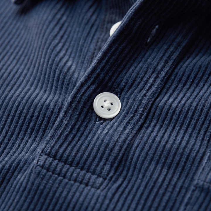 Close-up of navy corduroy polo placket with white button and ribbed texture