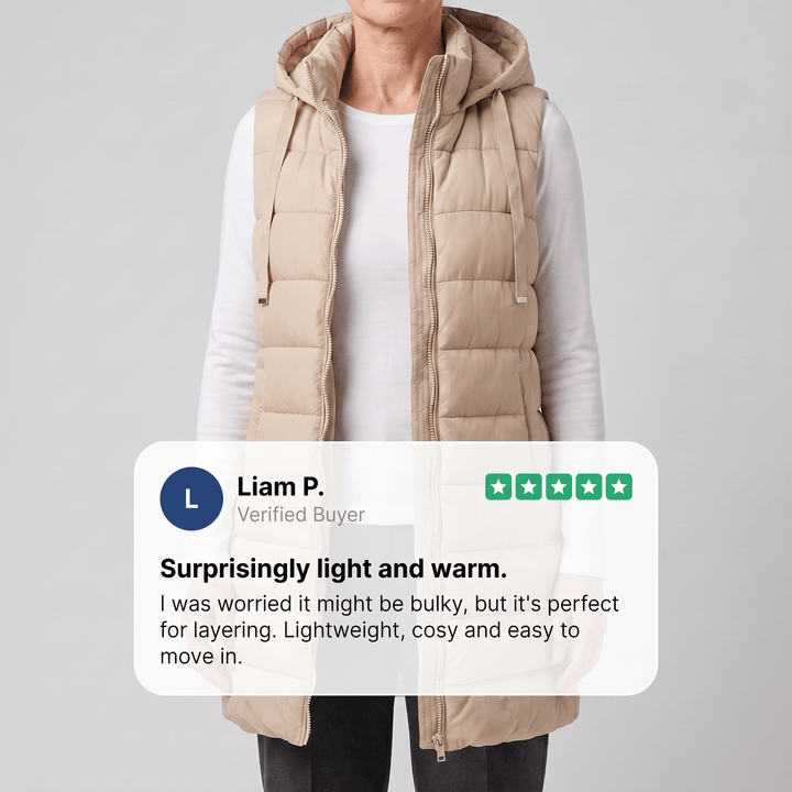 Long beige puffer vest with attached hood and front zipper, worn over a white top